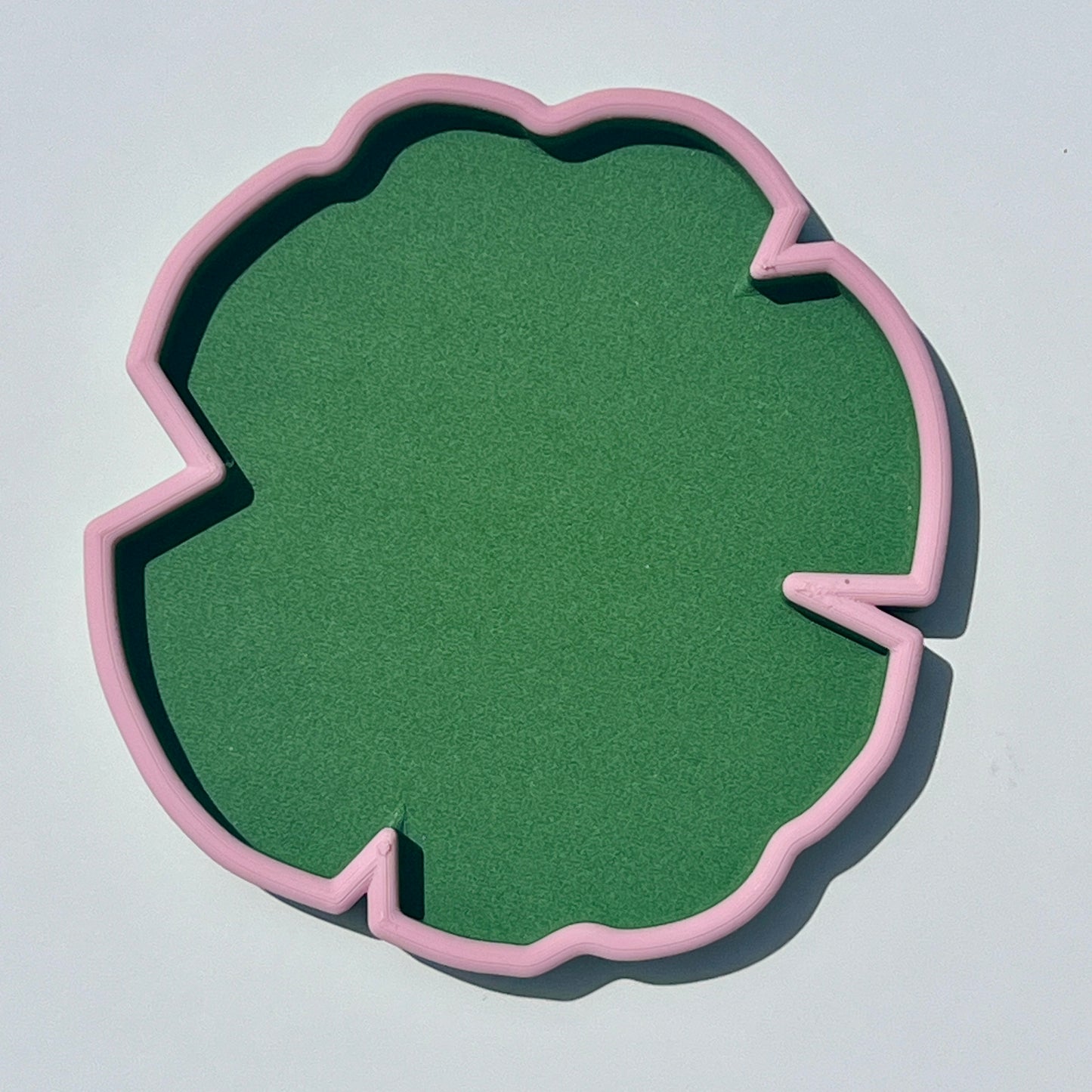 Matcha green lily pad-shaped 3D printed trinket tray with sakura pink edging.