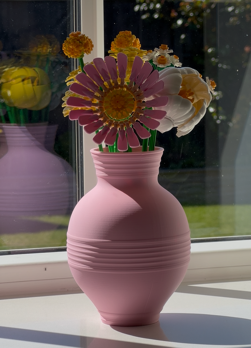 Pink vase with flowers on a windowsill 