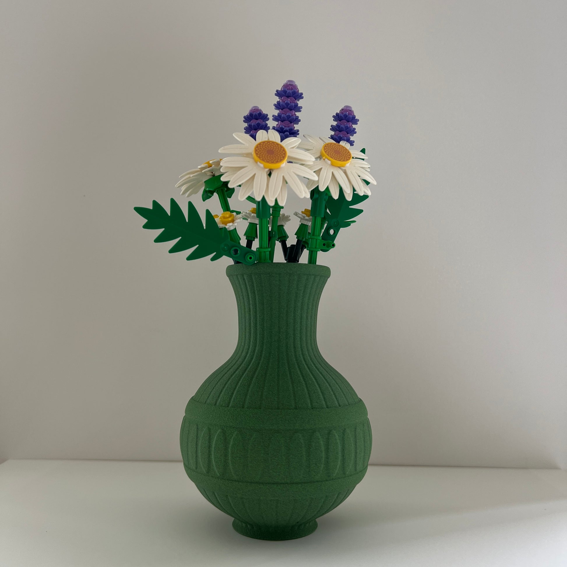 Green vase with floral arrangement on a plain background