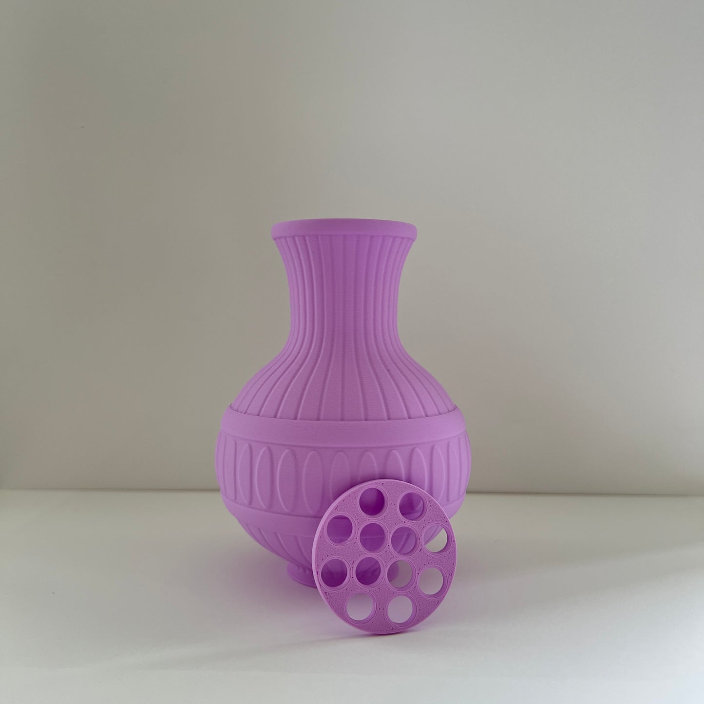 Purple textured vase on a white surface with a light gray background